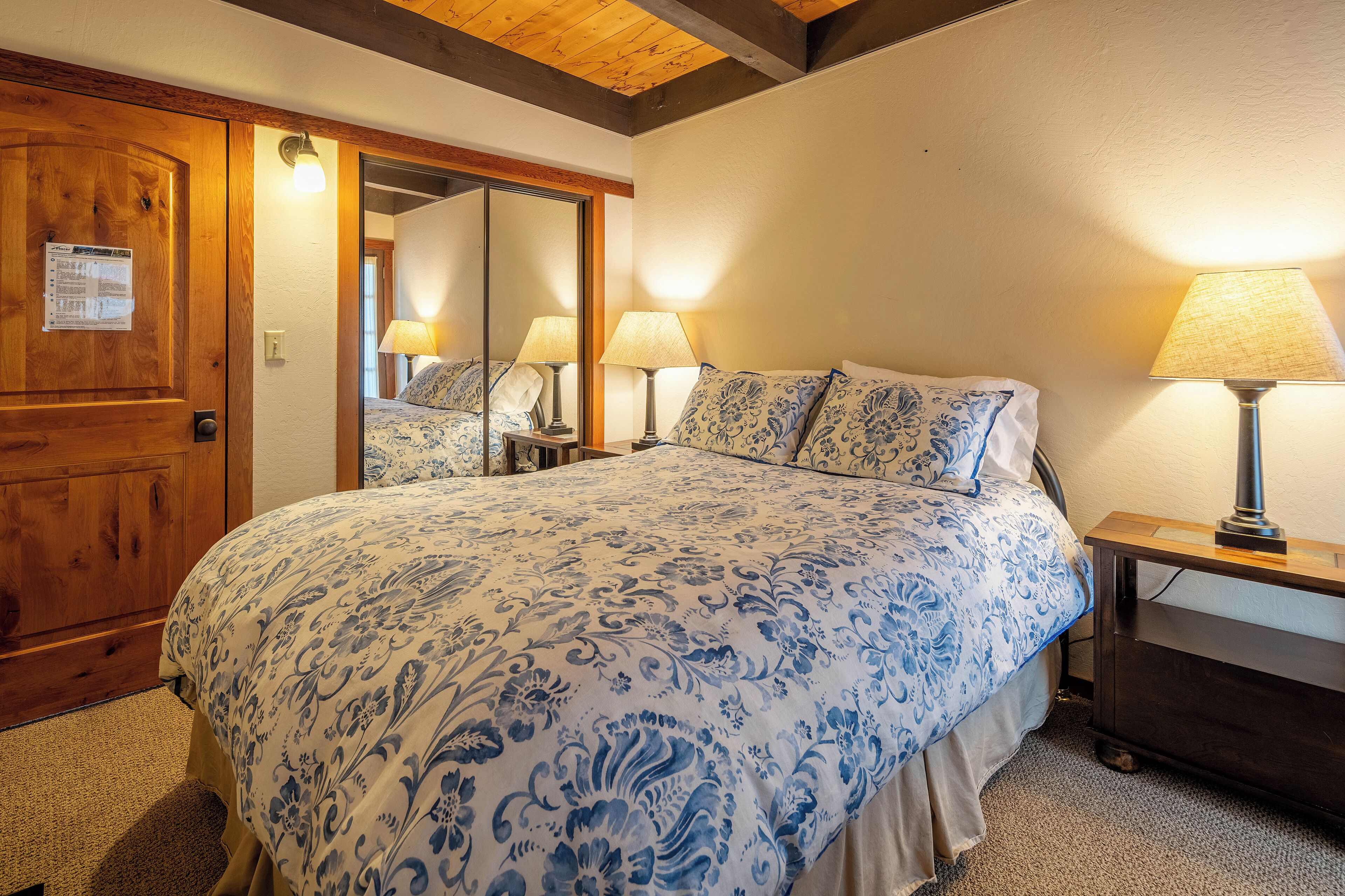 A bedroom with a large bed, wooden door, and two bedside lamps.