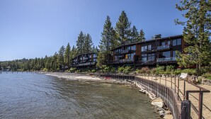 A waterfront hotel with multiple balconies overlooking a clear lake, surrounded by dense forest. - Star Harbor # 04 by Hauserman Rentals (Tahoe City)