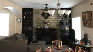 A spacious living room with a fireplace, a dining area with a table set for four, and a cozy seating area with a sofa and chairs. - Beautiful home in quiet neighborhood (Casa Grande)