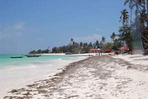 På stranden, hvit sand, solsenger og parasoller