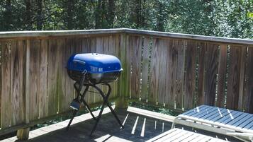 Une terrasse en bois avec un barbecue et une chaise longue.