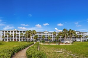 Ein mehrstöckiges Hotel mit Innenhof, Palmen und blauem Himmel.