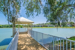 A wooden dock leading to a gazebo over a lake, surrounded by greenery and houses. - Water Front - Corner Location -1 Bedroom 1 Bath (Brandon)