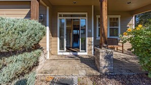 A house entrance with a covered porch, a sliding glass door, and a brick pathway leading to the door. - West Sail - Play & Work in Hood River! River & Mountain Views, Quiet, Walk to Downtown (Hood River)