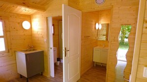 A wooden cabin interior with a wooden floor, a sink, a toilet, and a mirror.