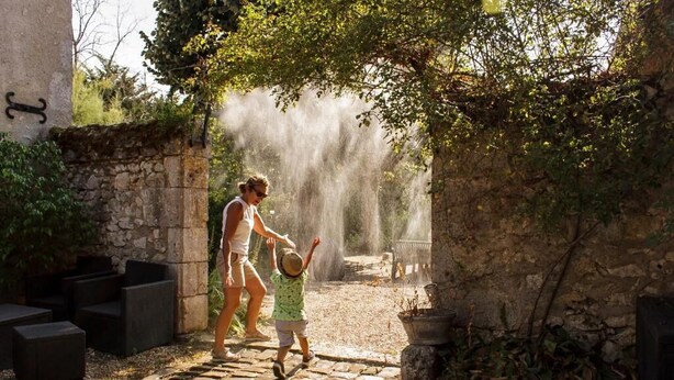 A stone pathway leading to a rustic outdoor seating area with a fountain.