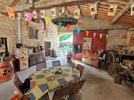 Un comedor rústico con una mesa grande, sillas de madera y un fondo de pared de piedra.