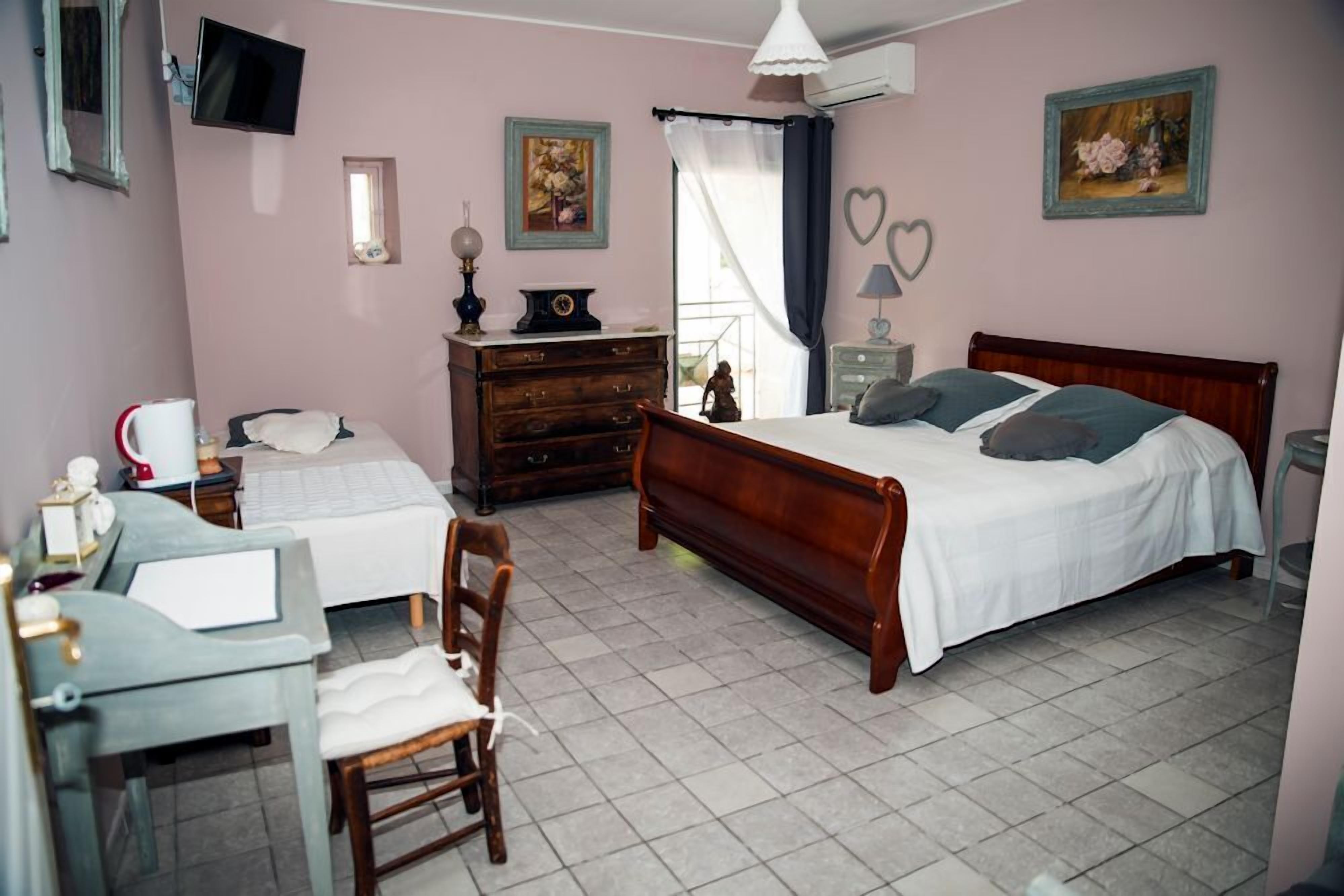 Une chambre à coucher comprenant un lit, une commode, un bureau, une chaise et un téléviseur.