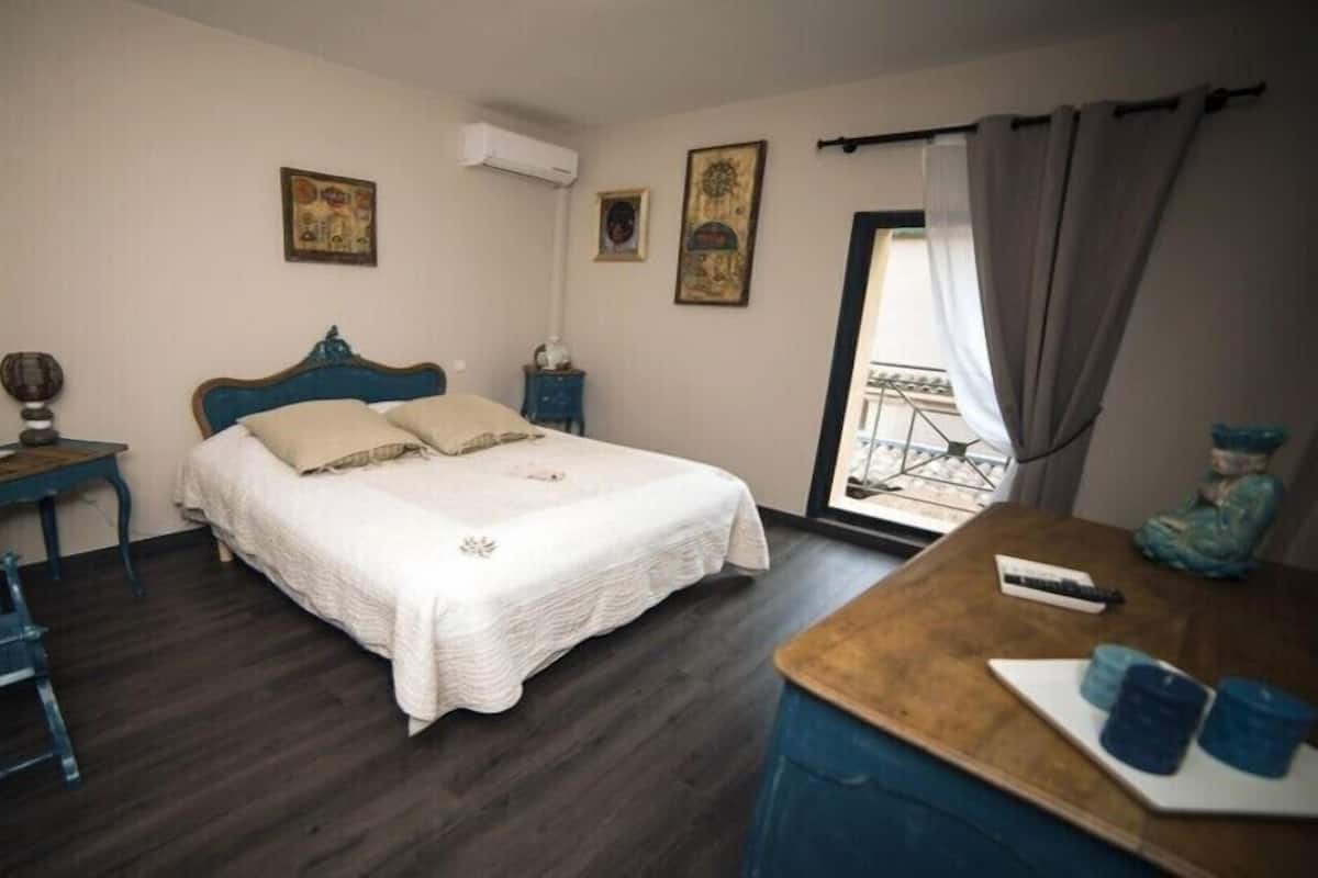A bedroom with a bed, a desk, a chair, and a window with curtains.