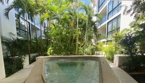 A pool surrounded by lush greenery and modern buildings.
