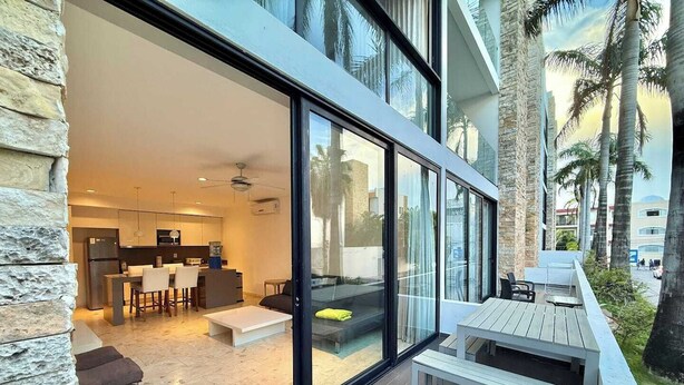 Un appartement moderne doté d’une cuisine, d’un coin repas et d’un balcon avec mobilier d’extérieur.