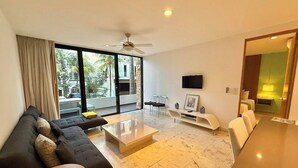 Un salon moderne avec un canapé, une table basse, un téléviseur et un balcon offrant une vue agréable.