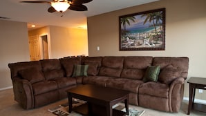 A living room with a brown sectional sofa, a wooden coffee table, and a ceiling fan. - Direct Lake Front Paradise Cove #1 In Reviews - Beach - Launch - Traeger Smoker (Clearlake)