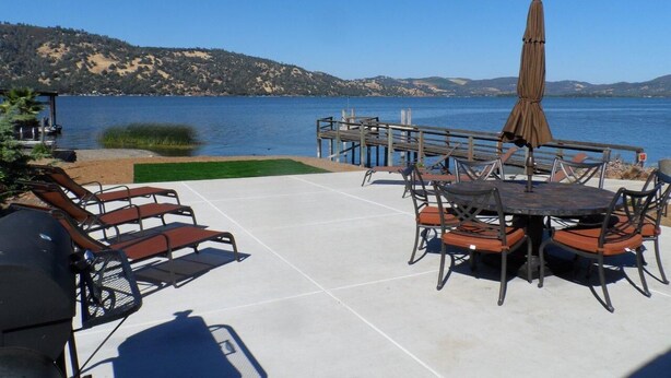 A patio with a table and chairs, a grill, and a view of the water. - Direct Lake Front Paradise Cove #1 In Reviews - Beach - Launch - Traeger Smoker (Clearlake)