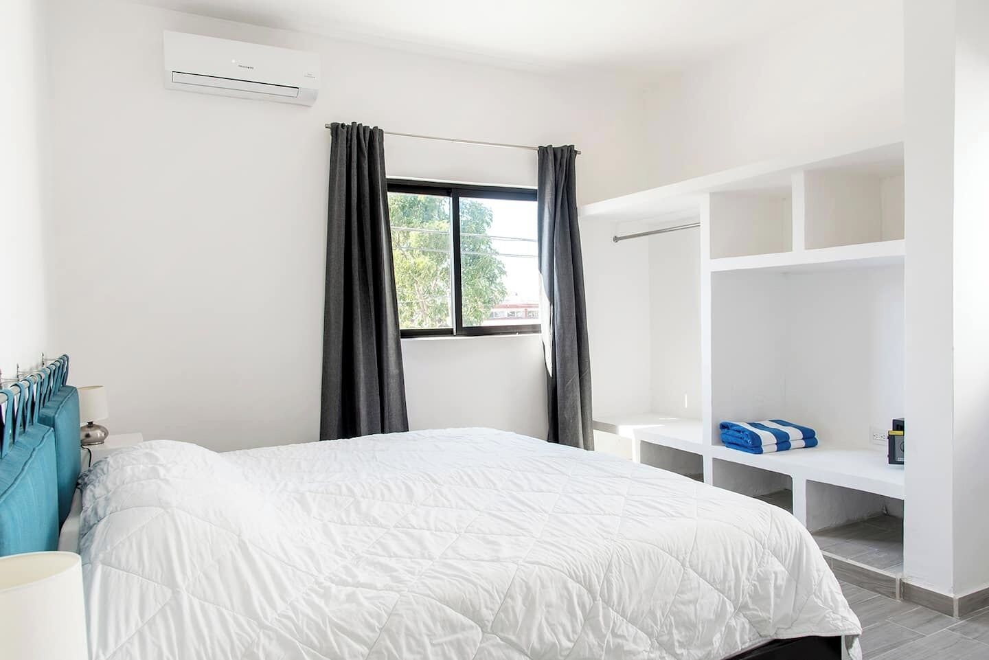 A hotel room with a bed, a wardrobe, and a window with curtains.