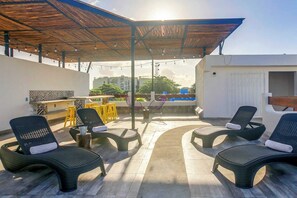An outdoor patio with seating, a bar area, and a view of the cityscape.