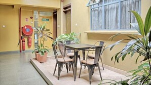 Un espace repas comprenant une table et des chaises, des plantes en pot et un extincteur.