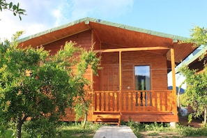 A wooden cabin with a porch, surrounded by greenery. - Yildiz Pension Bungalows (Kemer)
