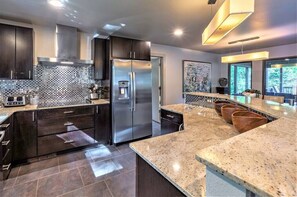 Una cocina moderna con armarios oscuros, un refrigerador de acero inoxidable y una encimera de granito.