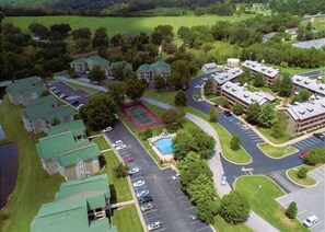 Vista aérea de uma área residencial com vários edifícios, piscina e quadra de tênis.