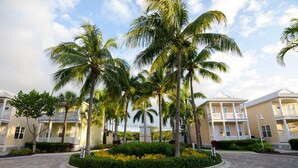 En hotellinnergård med palmer, en stenlagd gångväg och en byggnad med balkonger.