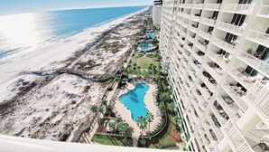 Ein Hochhaus-Hotel mit mehreren Balkonen mit Blick auf einen Strand und einen Poolbereich.