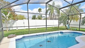 A covered swimming pool with clear blue water, surrounded by a white fence and palm trees. - Beautiful Pool Home With Kid's Play Room - Close to Theme Parks & Attractions (Kissimmee)