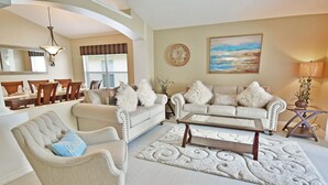 A spacious living room with a dining area, featuring a sofa set, armchairs, a coffee table, and a rug. - Beautiful Pool Home With Kid's Play Room - Close to Theme Parks & Attractions (Kissimmee)