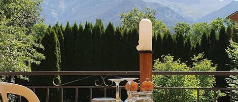 A table set outdoors with a mountain view, a wooden spoon, a glass, and a napkin holder.
