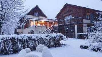 Un espacio exterior cubierto de nieve con un edificio que tiene un balcón y una escalera que lleva a la entrada.