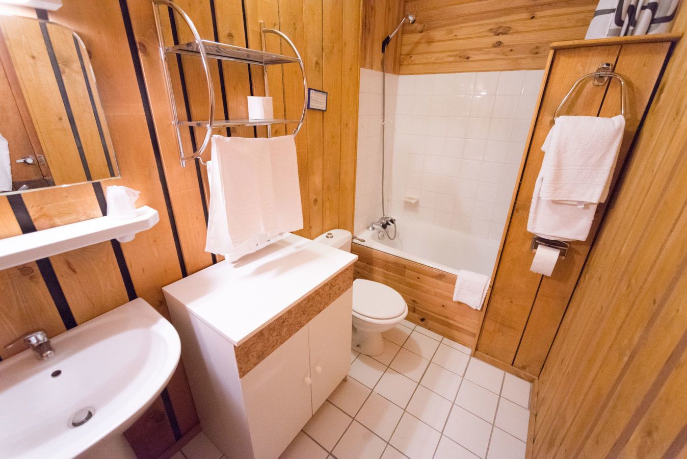 A wooden bathroom with a sink, toilet, and shower.