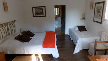 Habitación de hotel con dos camas, piso de madera, una mesita y una silla.