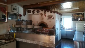 Una cocina con horno de leña, electrodomésticos de acero inoxidable y una vitrina de vidrio.
