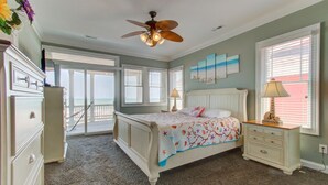 A bedroom with a bed, dresser, nightstand, and a ceiling fan.