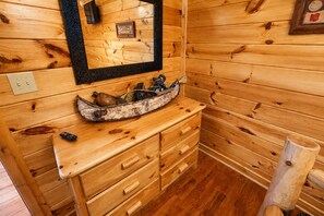 A wooden cabin interior with a wooden bench, a mirror, and a rustic decoration on the wall.