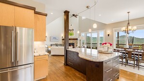 Een moderne keuken met een groot eiland, roestvrijstalen apparatuur en uitzicht op de omgeving.