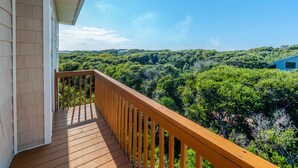 A wooden deck with a railing overlooking a dense forest and a distant hill. - Callalily | Gorgeous Ocean Views in Topsail Beach! (Topsail Beach)