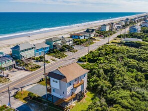 Eine Wohngegend an der Küste mit Häusern direkt am Strand, einer klaren Straße und dichter Vegetation.