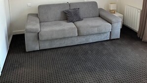 Una sala de estar moderna con un sofá gris, un televisor de pantalla plana montado en la pared y una alfombra estampada.