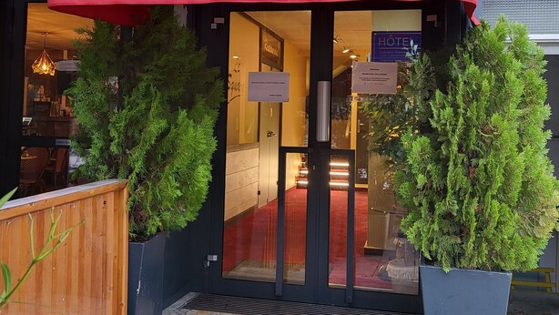 Entrada de un hotel con toldo rojo que indica “RÉCEPTION HOTEL Le Square.”