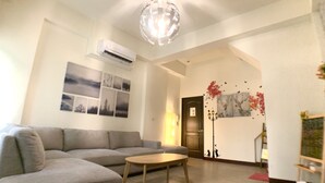 A living room with a grey sofa, a wooden coffee table, and a ceiling light fixture. - Partyport-Hai (Tainan)