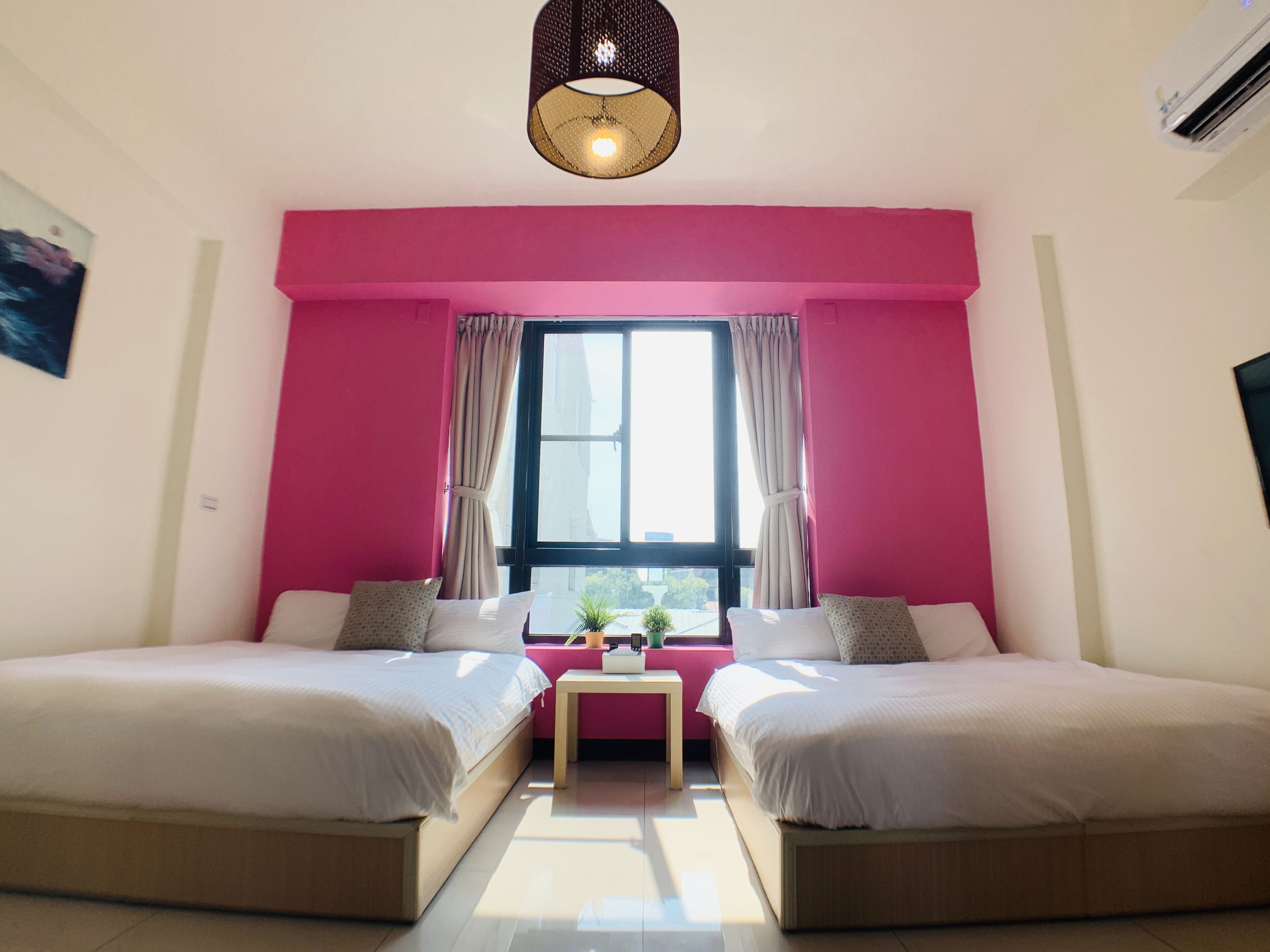 Una habitación con dos camas, una mesita y una ventana con cortinas.