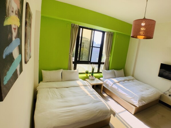 A room with two beds, a small table, a window with curtains, and a hanging light fixture. - Partyport-Hai (Tainan)