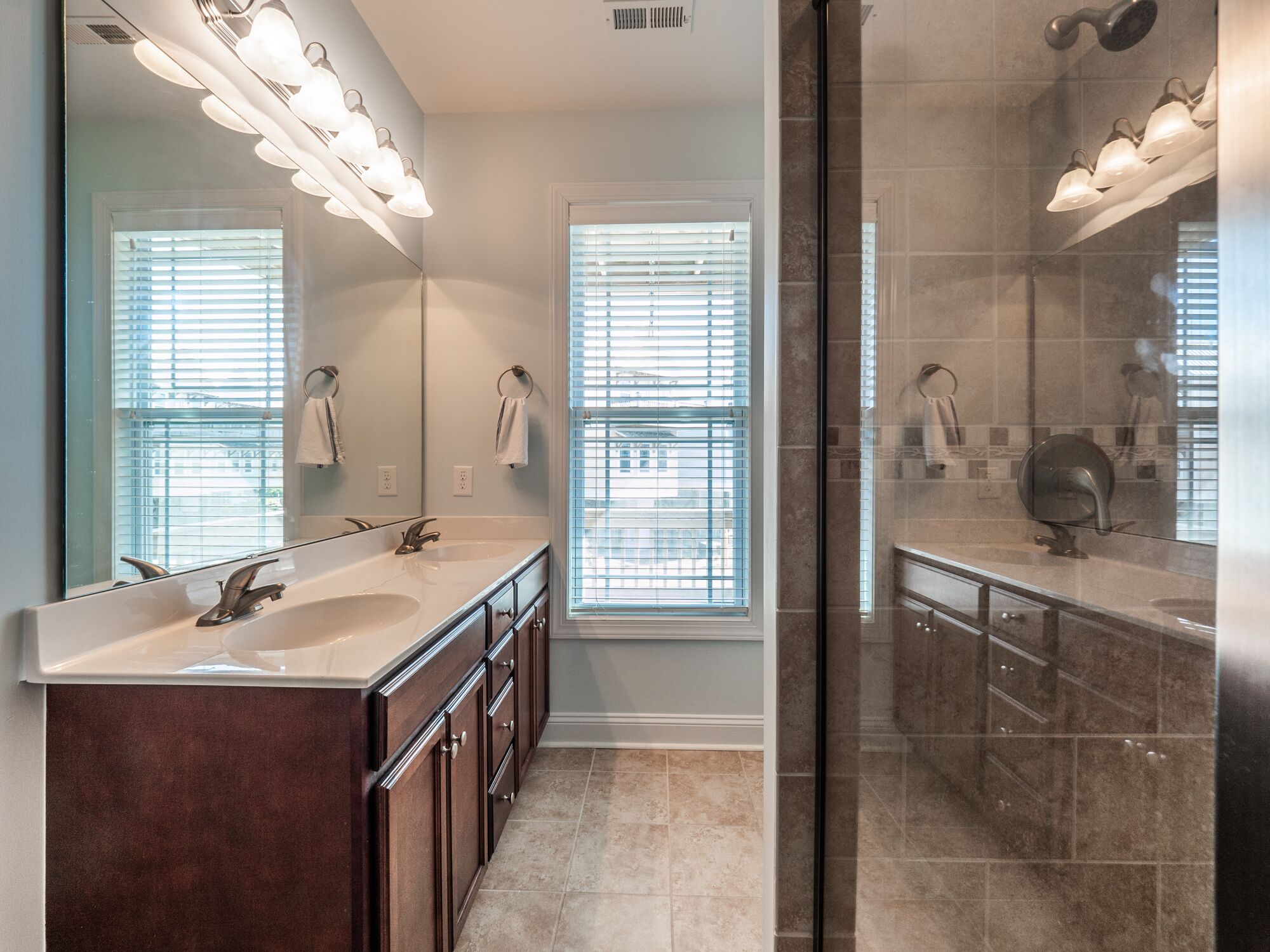 Une salle de bain moderne avec deux lavabos, un grand miroir et un espace douche.