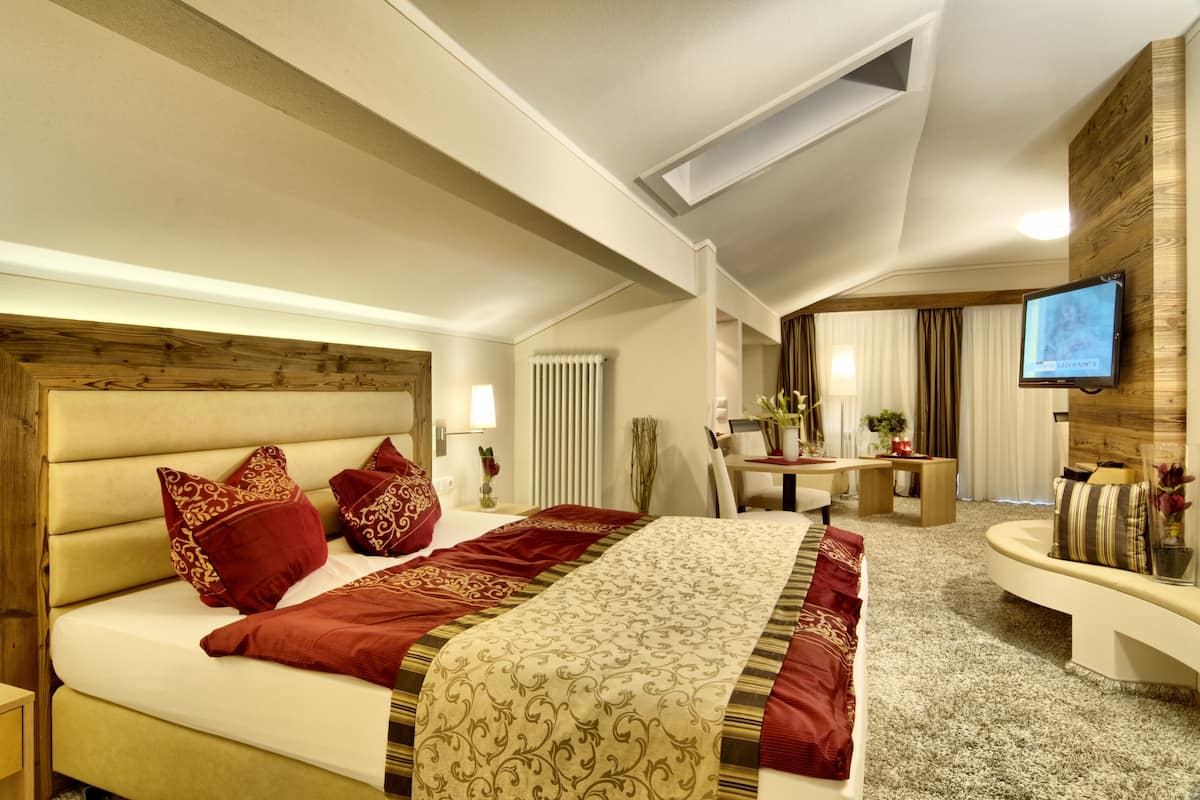 A modern hotel room with a large bed, a desk, and a television.
