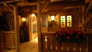 Interior de una cabaña de madera con una escalera, paredes de madera y un arreglo floral.
