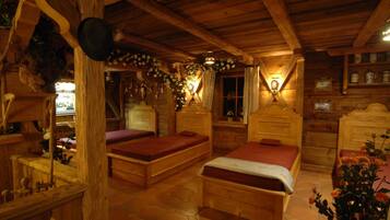 A rustic wooden room with two wooden beds, a wooden dresser, and a window with curtains.