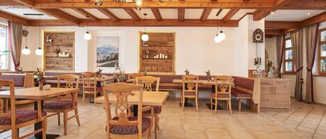 Ein Restaurant mit Holztischen und -bänken, einer Kristallleuchtre und einer Wanduhr.