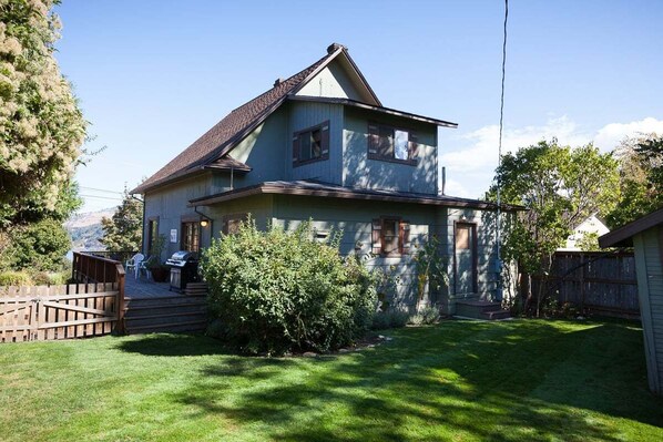 A two-story house with a sloped roof, a front porch, and a small front yard.