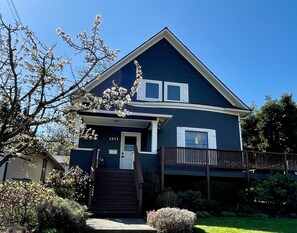 A two-story house with a dark blue exterior, white trim, and a front porch with steps leading to a door marked "1211".
